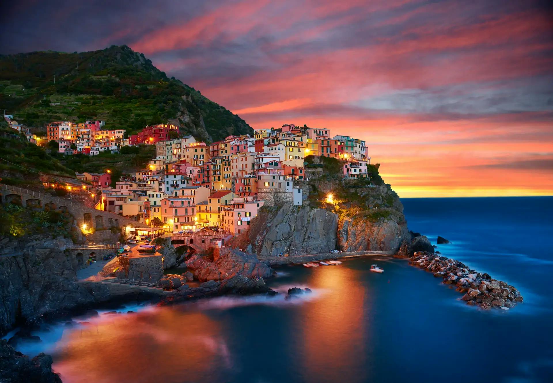 A cliffside village at dusk surrounded by water